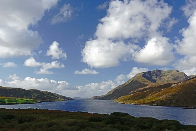 A long stretch of water running between steep mountains under summer cloud