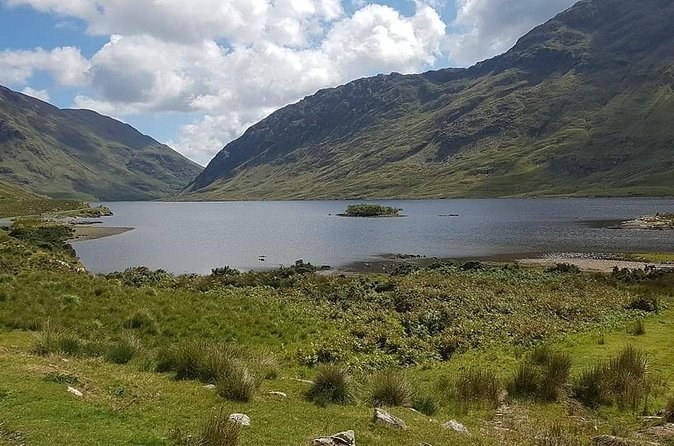 A lough with a small island, in a valley between steep green mountains